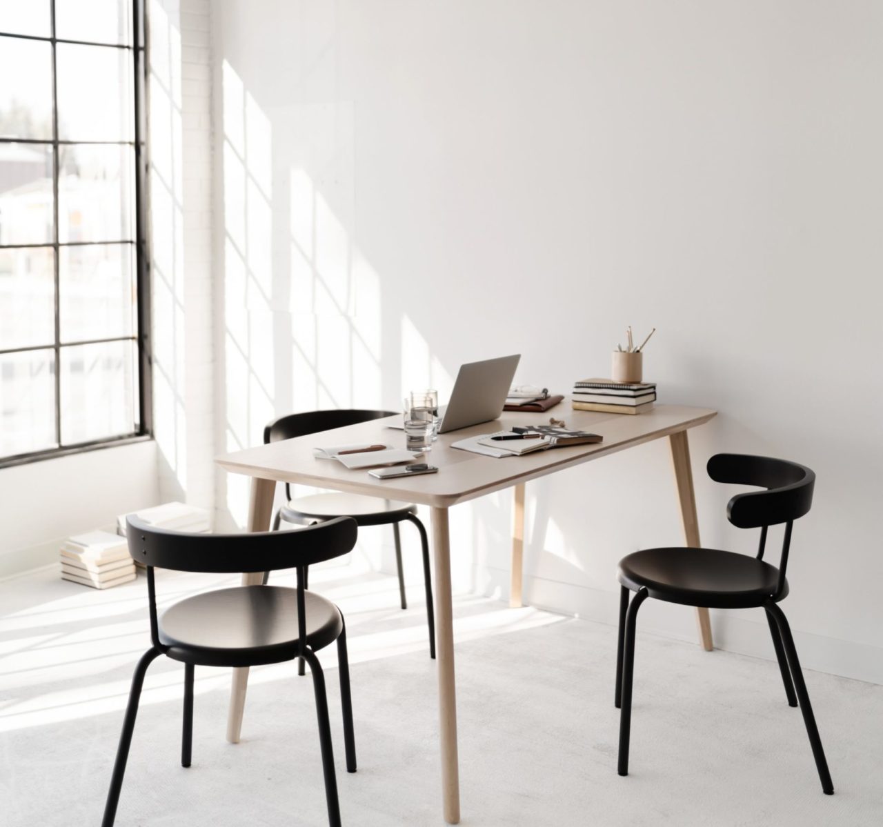 Desk and three chairs in a sunny office space